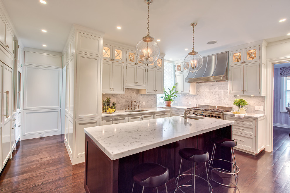 Photo of a large transitional l-shaped eat-in kitchen in New York with a single-bowl sink, louvered cabinets, white cabinets, granite benchtops, beige splashback, marble splashback, stainless steel appliances, dark hardwood floors, with island, brown floor and beige benchtop.