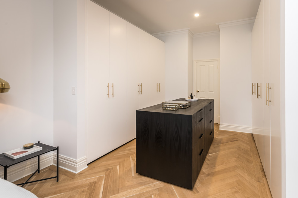 Photo of a mid-sized contemporary gender-neutral dressing room in Adelaide with flat-panel cabinets, black cabinets, light hardwood floors and brown floor.