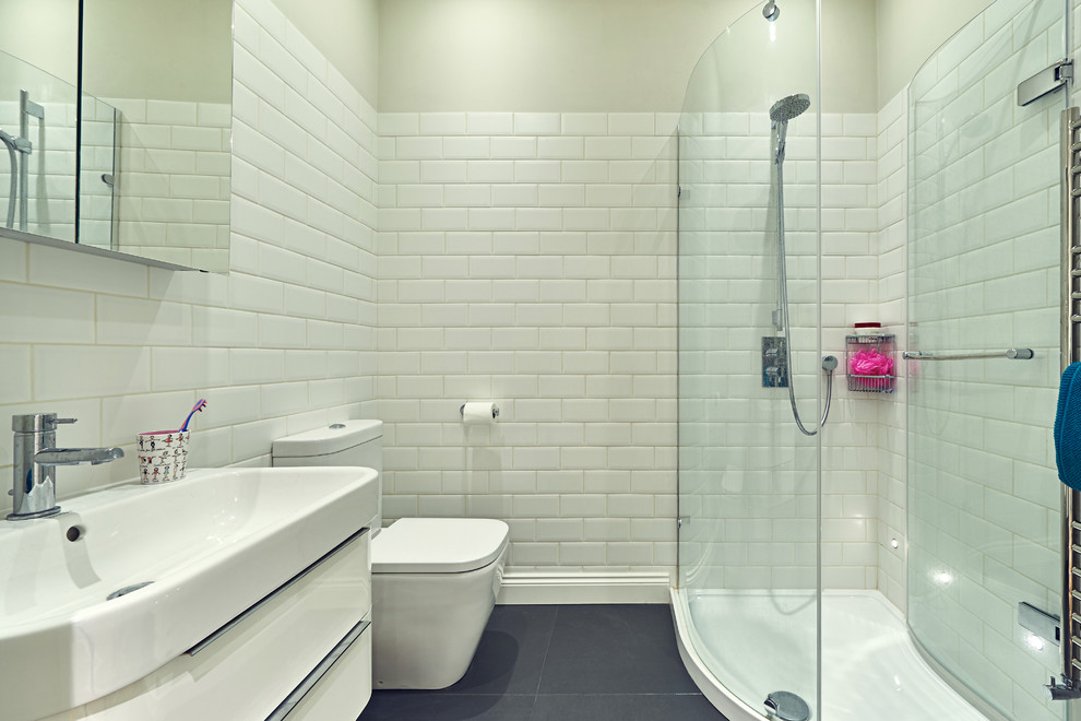 This is an example of a mid-sized contemporary 3/4 bathroom in London with a console sink, flat-panel cabinets, white cabinets, a corner shower, a two-piece toilet, white tile, subway tile and white walls.