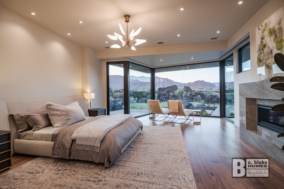 Geräumiges Modernes Hauptschlafzimmer mit beiger Wandfarbe, braunem Holzboden, Kamin, Kaminumrandung aus Stein und braunem Boden in Salt Lake City