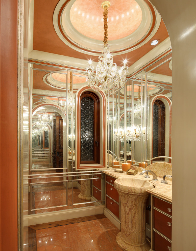 Expansive traditional powder room in Los Angeles with furniture-like cabinets, dark wood cabinets, beige tile, pink walls, marble floors, a pedestal sink and marble benchtops.