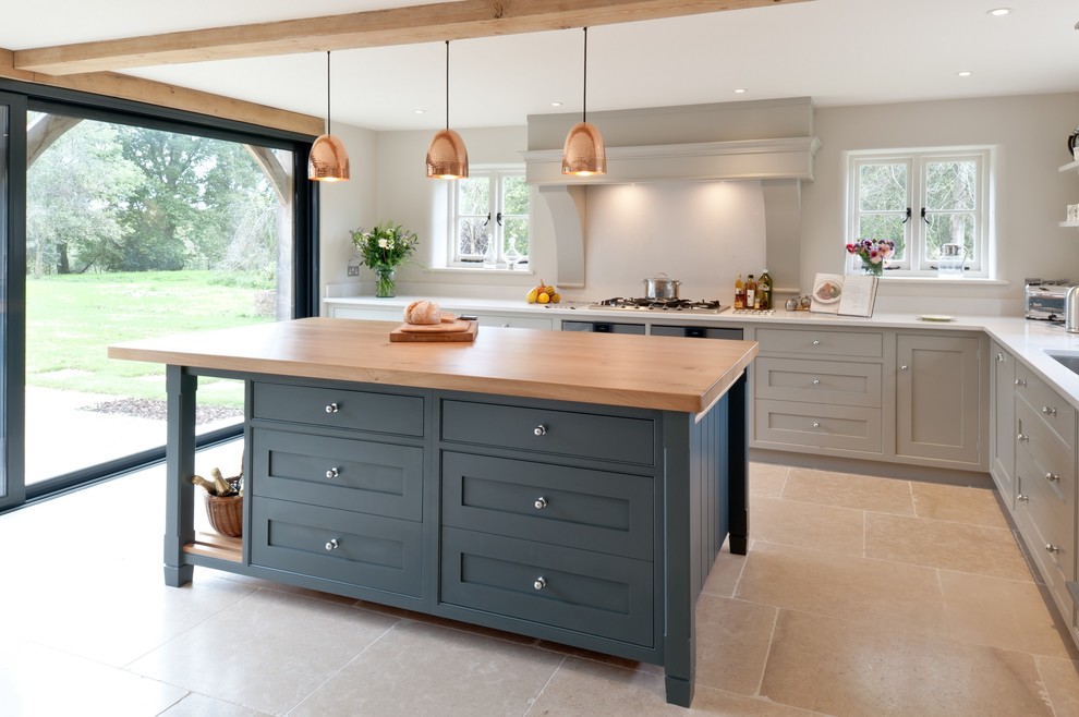 Photo of a large country l-shaped eat-in kitchen in Kent with flat-panel cabinets, blue cabinets, solid surface benchtops, white splashback, stainless steel appliances, limestone floors and with island.