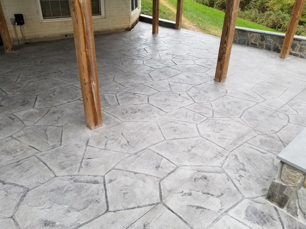 Large tropical backyard patio in Other with stamped concrete.