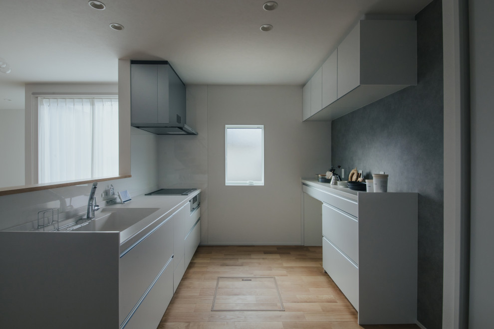 Inspiration pour une cuisine ouverte linéaire design avec des portes de placard blanches, une crédence blanche, un sol en bois brun, un sol beige, un plan de travail blanc et un plafond en papier peint.