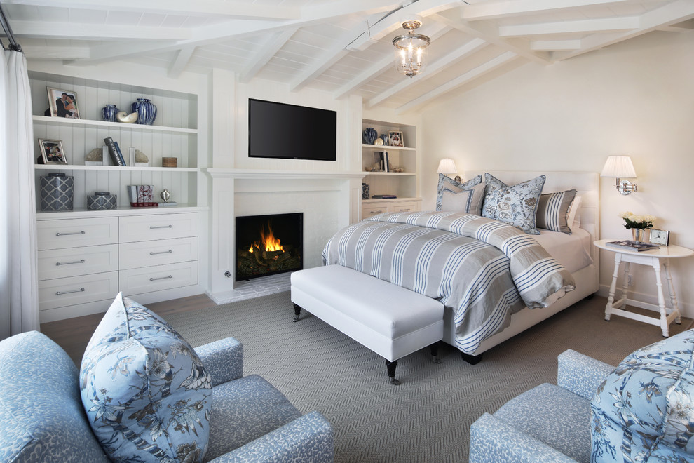 Inspiration for a beach style bedroom in Orange County with white walls, carpet, a standard fireplace and grey floor.