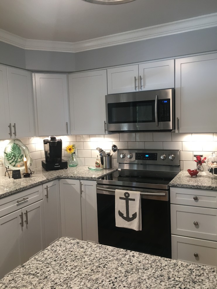 Design ideas for a transitional l-shaped open plan kitchen in Wilmington with an undermount sink, shaker cabinets, white cabinets, granite benchtops, white splashback, porcelain splashback, stainless steel appliances, medium hardwood floors and brown floor.