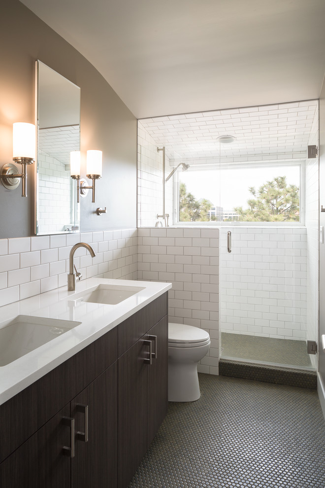 This is an example of a mid-sized transitional 3/4 bathroom in Denver with flat-panel cabinets, dark wood cabinets, an alcove shower, white tile, ceramic tile, grey walls, mosaic tile floors, an undermount sink, engineered quartz benchtops, a hinged shower door, a two-piece toilet, grey floor and white benchtops.