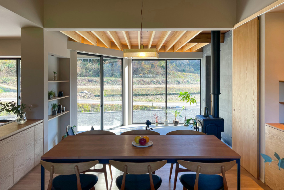 На фото: гостиная-столовая в стиле модернизм с белыми стенами, паркетным полом среднего тона, печью-буржуйкой, фасадом камина из бетона, коричневым полом, деревянным потолком и обоями на стенах с