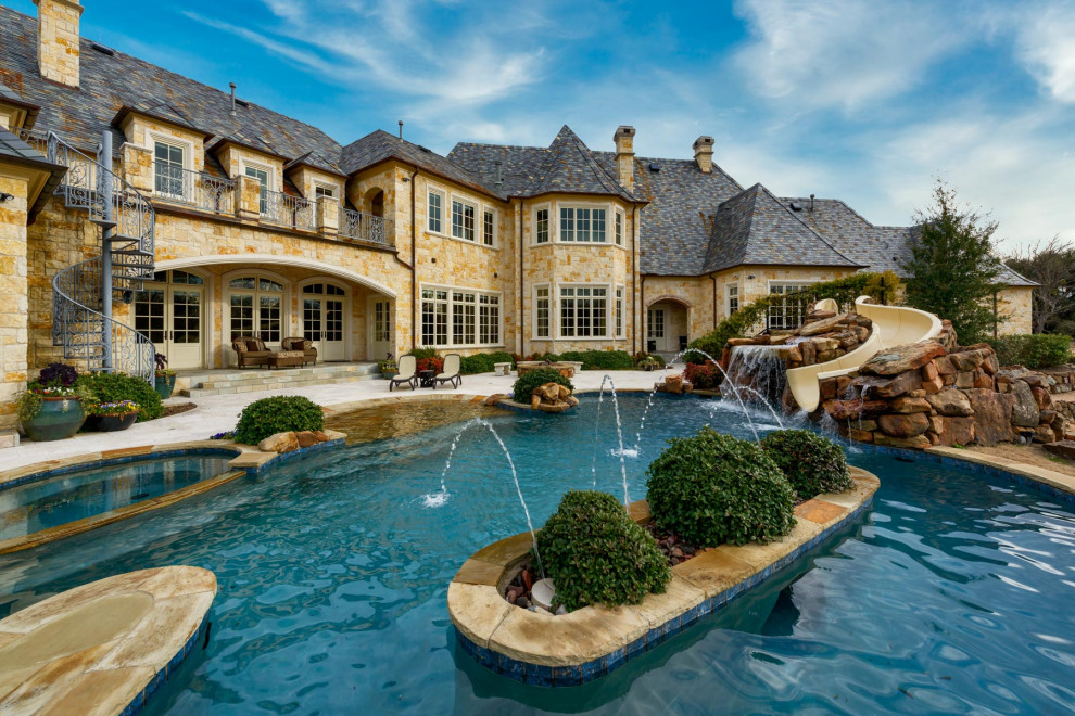 Photo of a large traditional backyard custom-shaped pool in Dallas with with a pool and natural stone pavers.