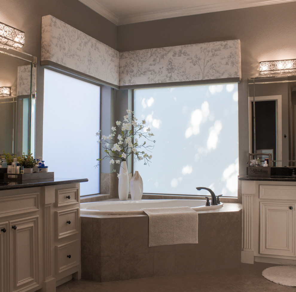 This is an example of a mid-sized transitional master bathroom in Houston with raised-panel cabinets, white cabinets, a corner tub, a corner shower, beige tile, ceramic tile, an undermount sink, granite benchtops, a hinged shower door, black benchtops, an enclosed toilet, a double vanity and a built-in vanity.