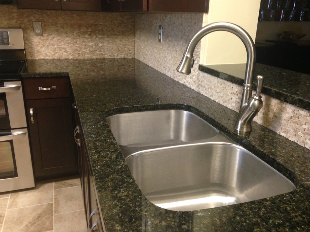 Mid-sized transitional l-shaped porcelain tile enclosed kitchen photo with an undermount sink, shaker cabinets, dark wood cabinets, granite countertops, beige backsplash, stone tile backsplash, stainless steel appliances and an island