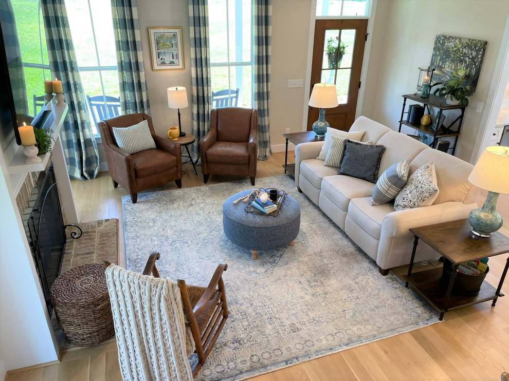 Design ideas for a mid-sized country living room in Raleigh with beige walls, light hardwood floors, a two-sided fireplace and a brick fireplace surround.