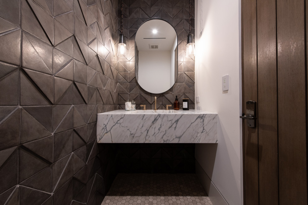 Design ideas for a mid-sized transitional powder room in Orange County with white cabinets, a one-piece toilet, ceramic tile, black walls, marble floors, an integrated sink, marble benchtops, white floor, white benchtops and a floating vanity.