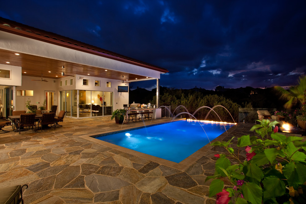 Mid-sized mountain style backyard stone and rectangular infinity pool photo in Austin