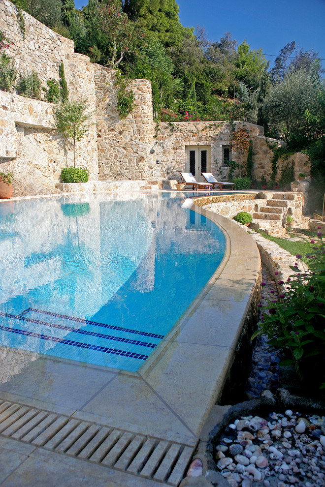 Photo of a mediterranean custom-shaped pool in Other with natural stone pavers.