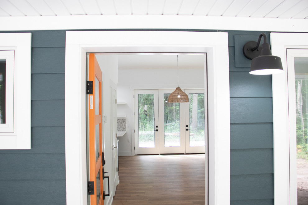 Esempio di un ingresso o corridoio minimalista di medie dimensioni con pareti blu, pavimento in laminato, una porta arancione, pavimento marrone e soffitto a volta