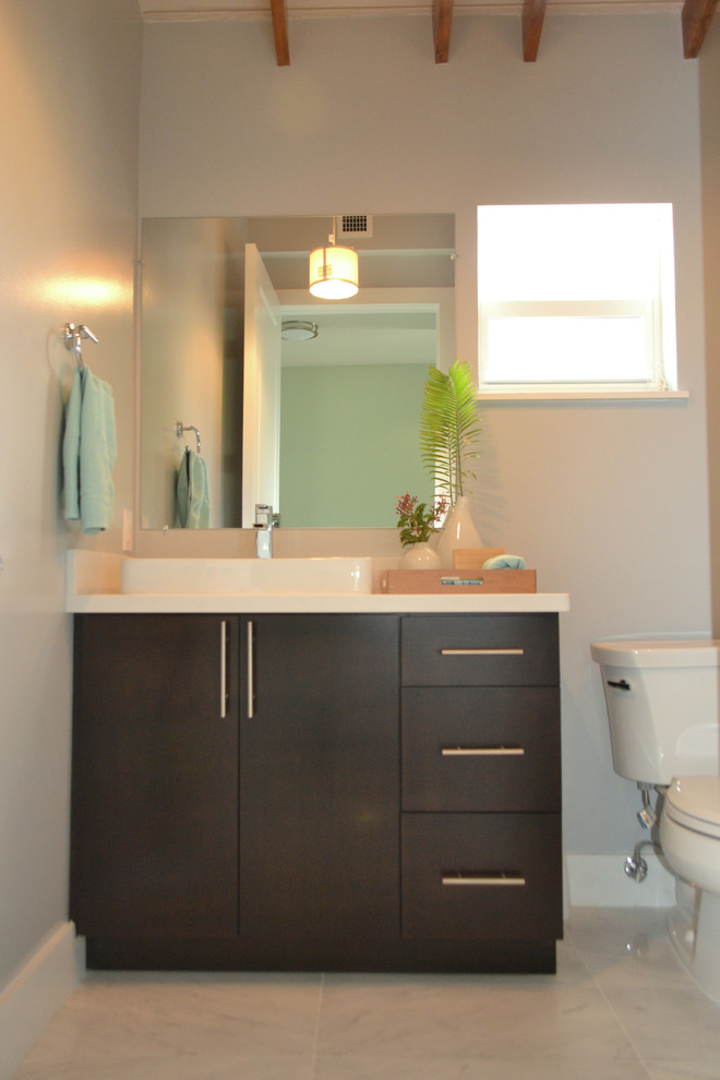 This is an example of a mid-sized tropical master bathroom in Miami with flat-panel cabinets, dark wood cabinets, a drop-in tub, a corner shower, a two-piece toilet, multi-coloured tile, matchstick tile, grey walls, a vessel sink, quartzite benchtops, marble floors and grey floor.