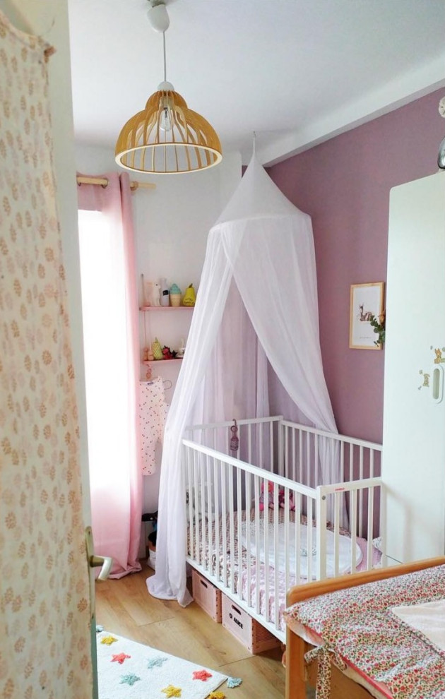 Idées déco pour une petite chambre de bébé fille moderne avec un mur rose, parquet clair, un sol beige et du papier peint.