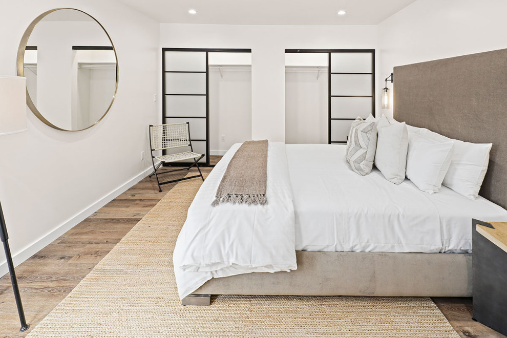 This is an example of a large classic master and grey and white bedroom in Los Angeles with white walls, medium hardwood flooring, no fireplace and brown floors.