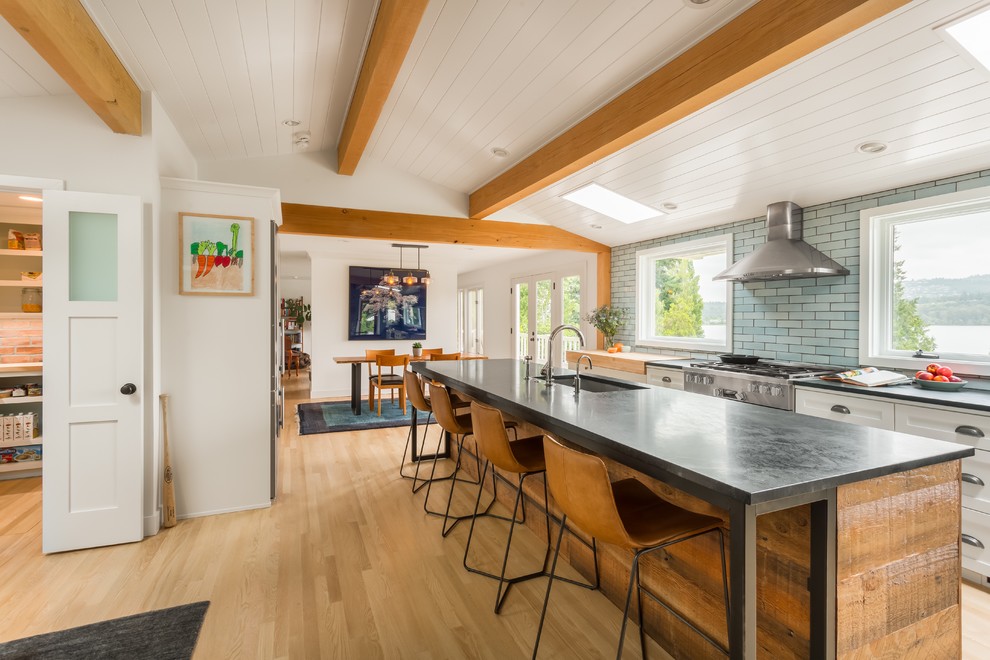 Transitional kitchen in Seattle with an undermount sink, shaker cabinets, white cabinets, blue splashback, stainless steel appliances, light hardwood floors, with island and beige floor.