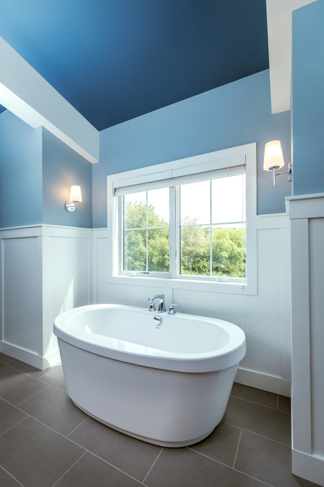 Inspiration for a mid-sized country master bathroom in Milwaukee with medium wood cabinets, a freestanding tub, a curbless shower, blue tile, blue walls, a drop-in sink, engineered quartz benchtops, grey floor, a hinged shower door, an enclosed toilet, a double vanity, a freestanding vanity, vaulted and decorative wall panelling.