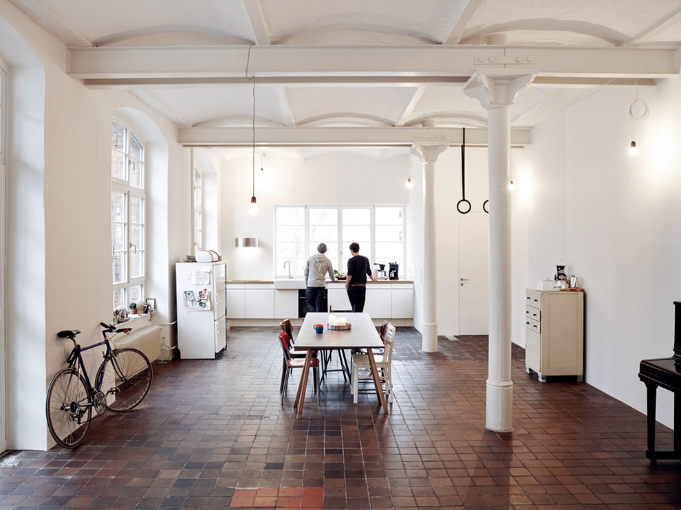Photo of a mid-sized industrial l-shaped open plan kitchen in Berlin with brick floors and red floor.