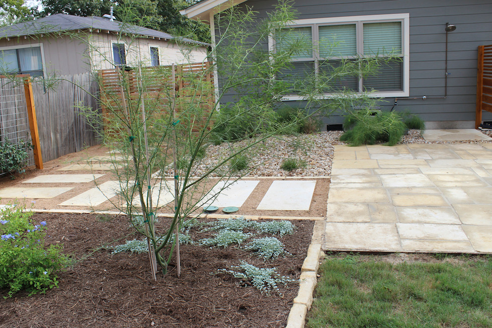 Mid-sized modern backyard patio in Austin with natural stone pavers.
