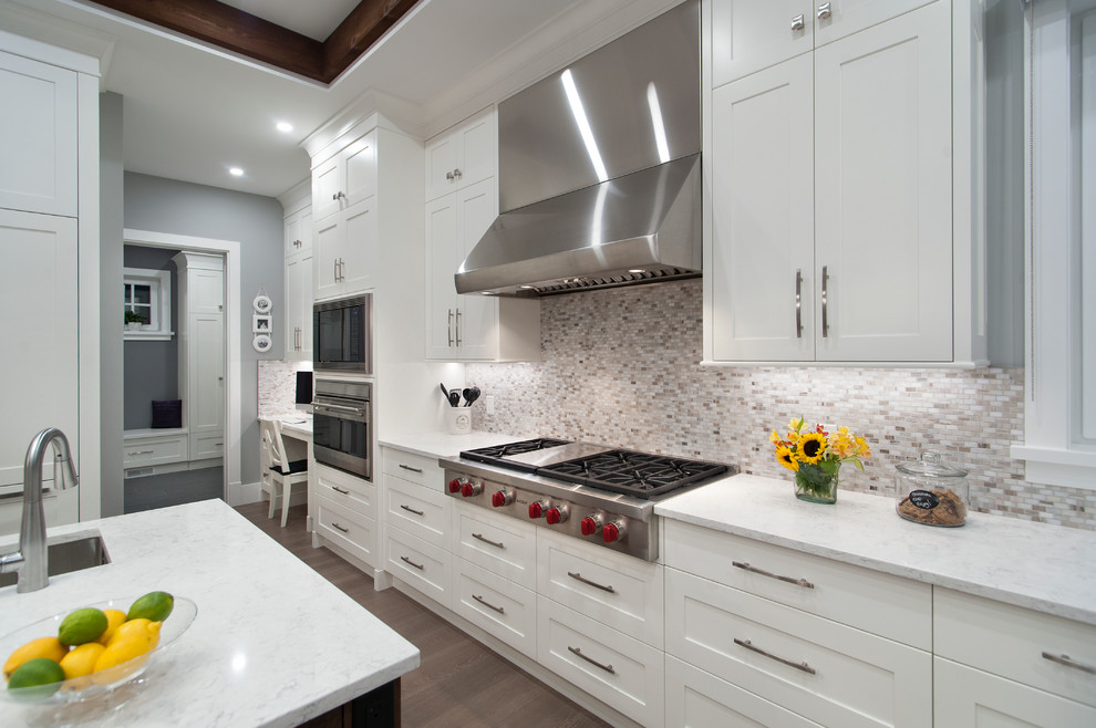 Inspiration for a transitional dark wood floor kitchen remodel in Vancouver with an undermount sink, shaker cabinets, white cabinets, beige backsplash, mosaic tile backsplash, stainless steel appliances and an island