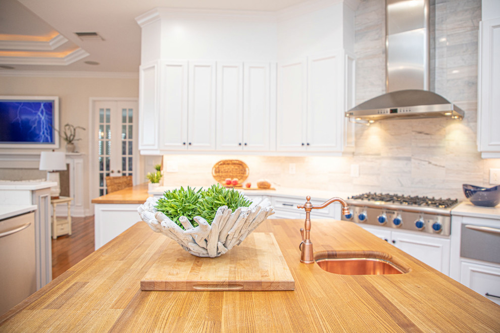 Immagine di una cucina minimal di medie dimensioni con lavello sottopiano, ante in stile shaker, ante bianche, top in granito, elettrodomestici in acciaio inossidabile, pavimento in legno massello medio e top bianco