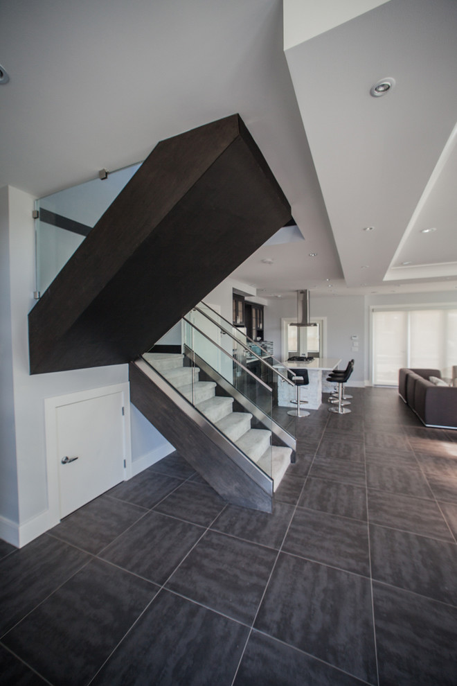 Photo of a mid-sized contemporary carpeted u-shaped staircase in Vancouver with carpet risers and glass railing.