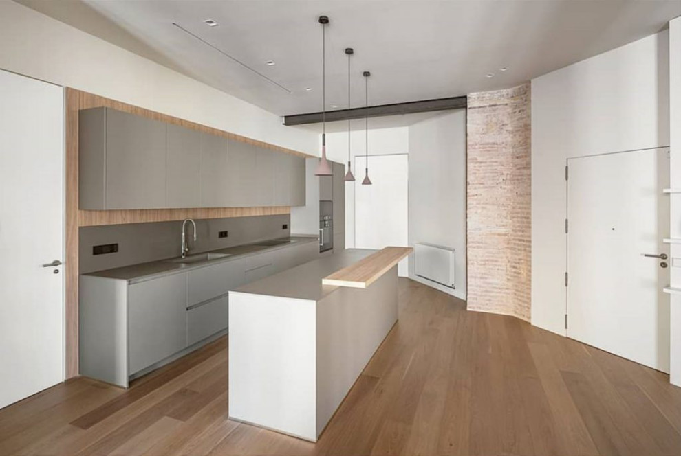 Inspiration för ett mellanstort funkis grå linjärt grått kök med öppen planlösning, med en integrerad diskho, släta luckor, grå skåp, grått stänkskydd, stänkskydd i cementkakel, integrerade vitvaror, mellanmörkt trägolv, en köksö och brunt golv