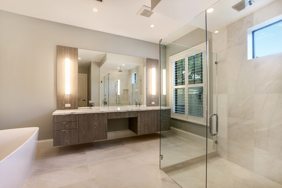 Photo of a mid-sized midcentury master bathroom in Miami with flat-panel cabinets, dark wood cabinets, a freestanding tub, a corner shower, a one-piece toilet, beige tile, porcelain tile, grey walls, porcelain floors, an undermount sink and engineered quartz benchtops.