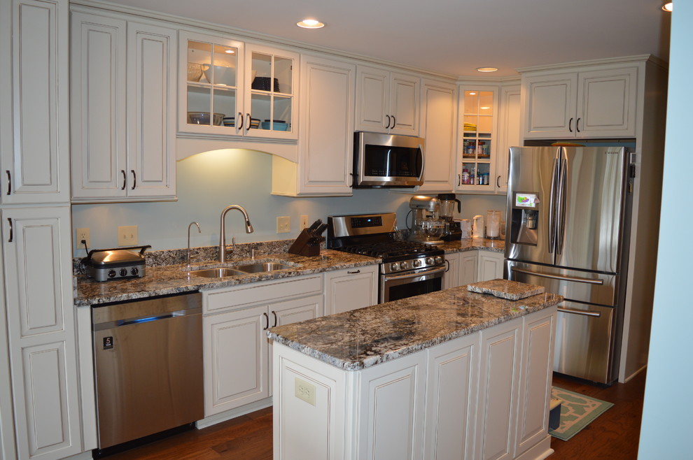 Large traditional l-shaped eat-in kitchen in Other with an undermount sink, raised-panel cabinets, white cabinets, granite benchtops, stainless steel appliances, medium hardwood floors and multiple islands.