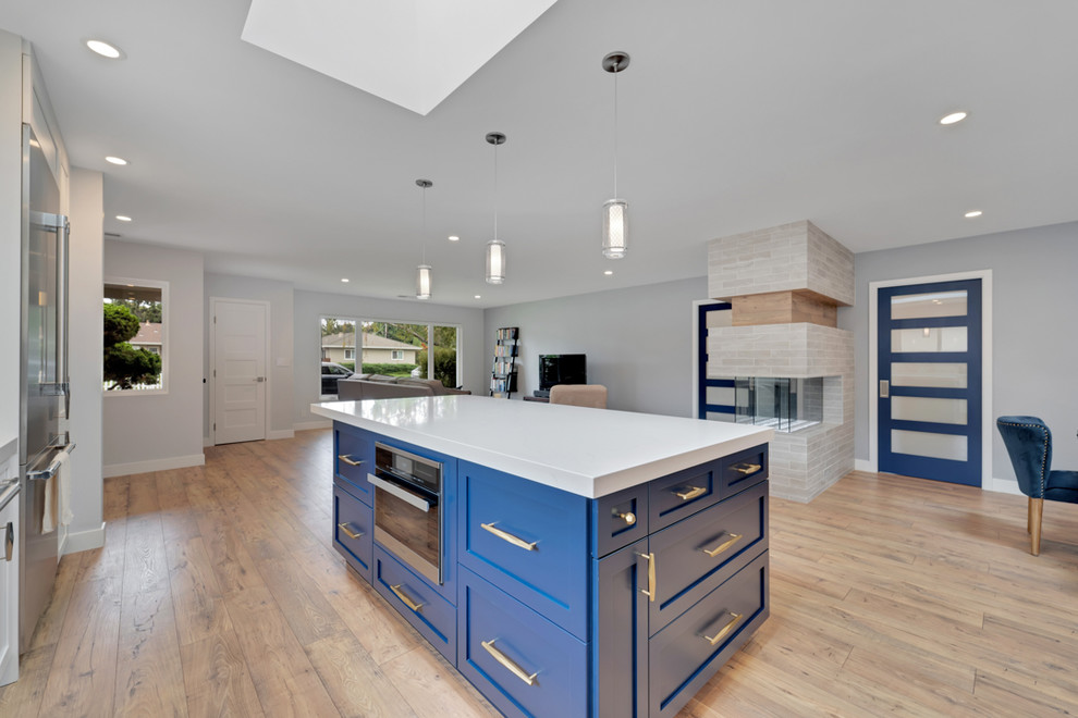 This is an example of a mid-sized modern l-shaped open plan kitchen in San Francisco with an undermount sink, shaker cabinets, quartz benchtops, ceramic splashback, stainless steel appliances, medium hardwood floors, with island and white benchtop.