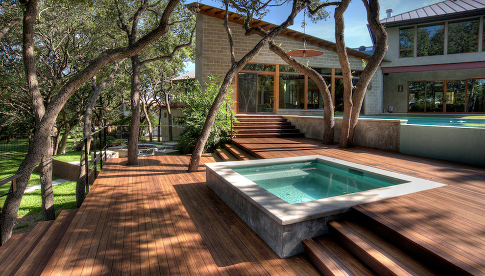 Design ideas for a contemporary backyard rectangular infinity pool in Austin with a hot tub and decking.