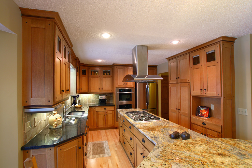 Inspiration for a mid-sized craftsman l-shaped light wood floor eat-in kitchen remodel in Minneapolis with an undermount sink, flat-panel cabinets, medium tone wood cabinets, laminate countertops, brown backsplash, ceramic backsplash, stainless steel appliances and an island