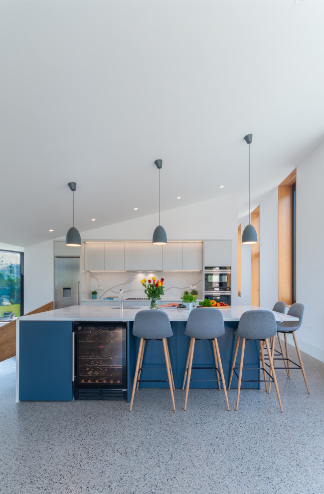 This is an example of a contemporary eat-in kitchen in Dublin with flat-panel cabinets, quartzite benchtops, stone slab splashback, with island and white benchtop.