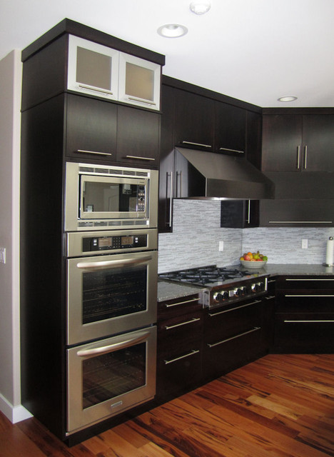View of the double wall ovens, built-in microwave, gas cooktop, and hood..