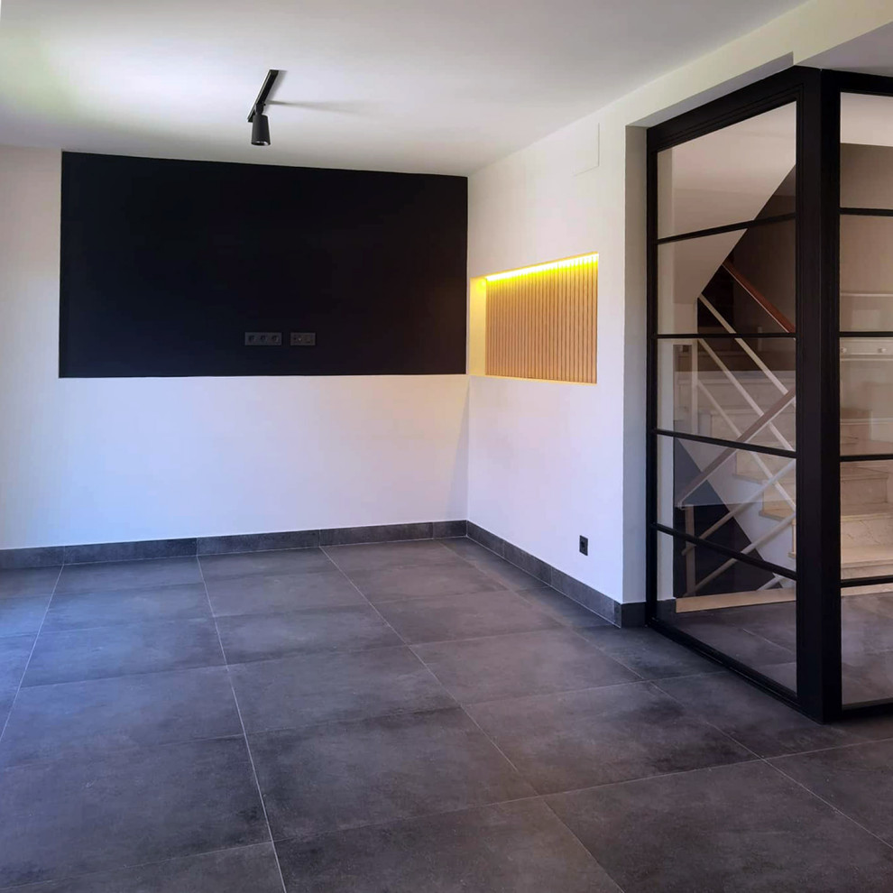Bild på ett mellanstort industriellt allrum med öppen planlösning, med svarta väggar, skiffergolv, en väggmonterad TV och svart golv