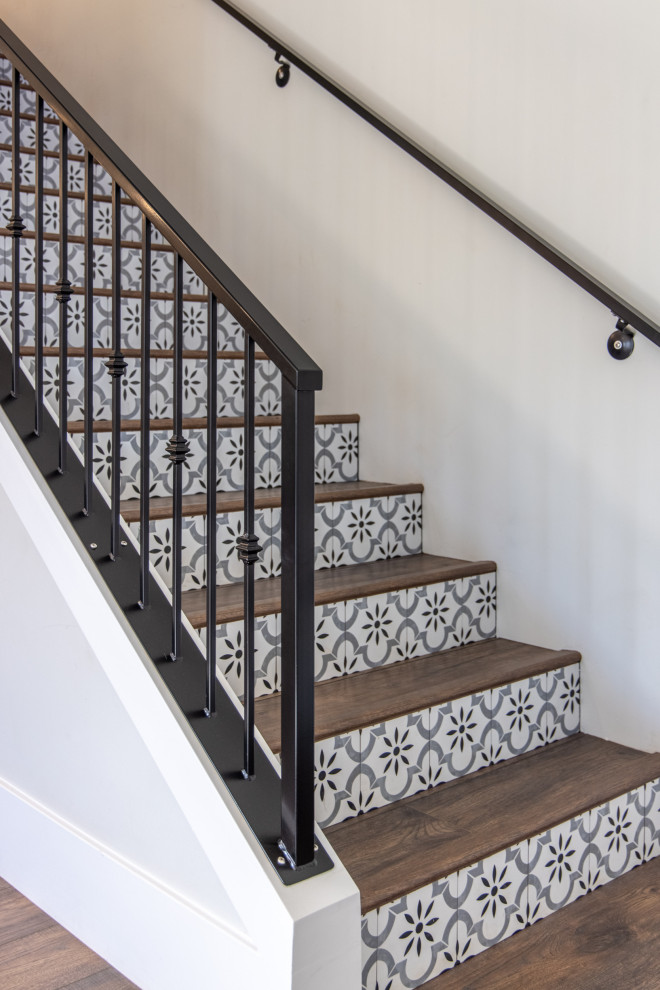 Modelo de escalera tradicional renovada con escalones de madera, contrahuellas con baldosas y/o azulejos y barandilla de metal