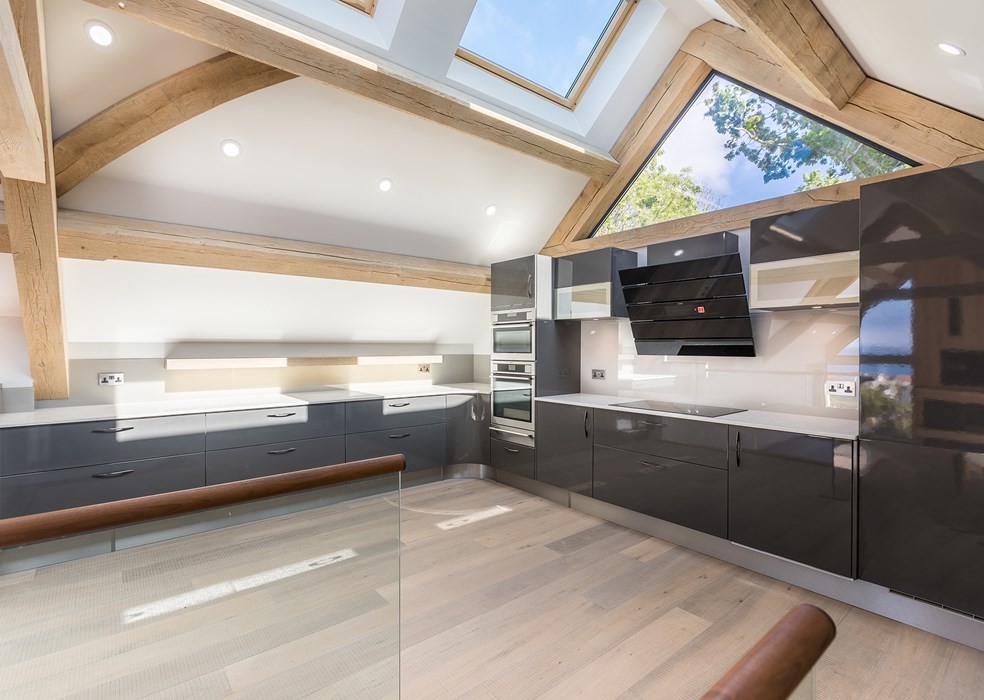 Design ideas for a large contemporary u-shaped open plan kitchen in Channel Islands with an integrated sink, flat-panel cabinets, black cabinets, granite benchtops, white splashback, panelled appliances, no island and white benchtop.