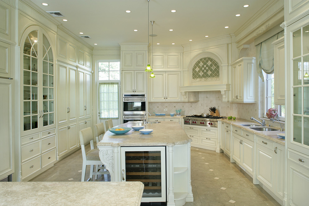 This is an example of a traditional kitchen in New York with a double-bowl sink, white cabinets, limestone benchtops and multiple islands.