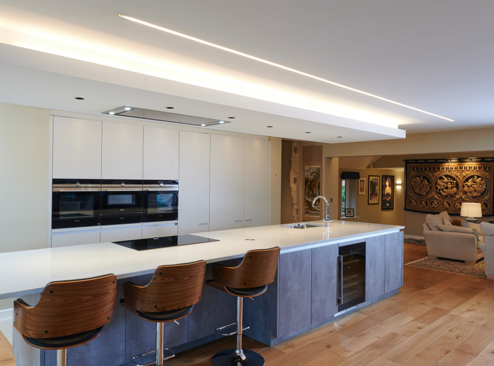 This is an example of a large contemporary single-wall open plan kitchen in Other with flat-panel cabinets, grey cabinets, an island and white worktops.