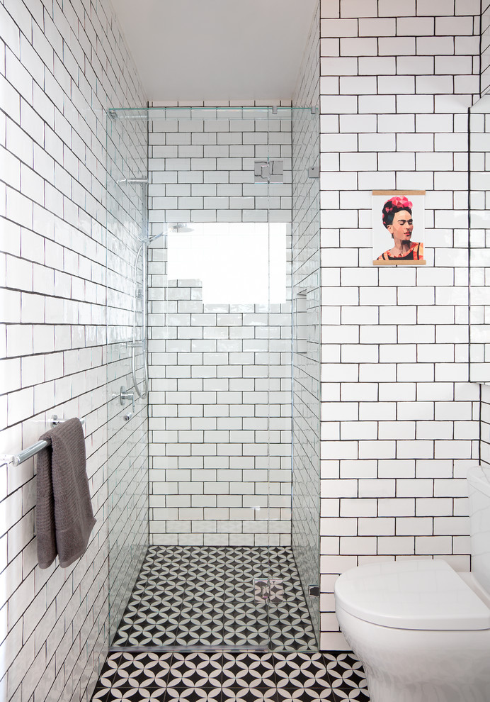 This is an example of a small contemporary bathroom in Melbourne with an alcove shower, a one-piece toilet, white tile, ceramic tile, white walls, mosaic tile floors, black floor and a hinged shower door.