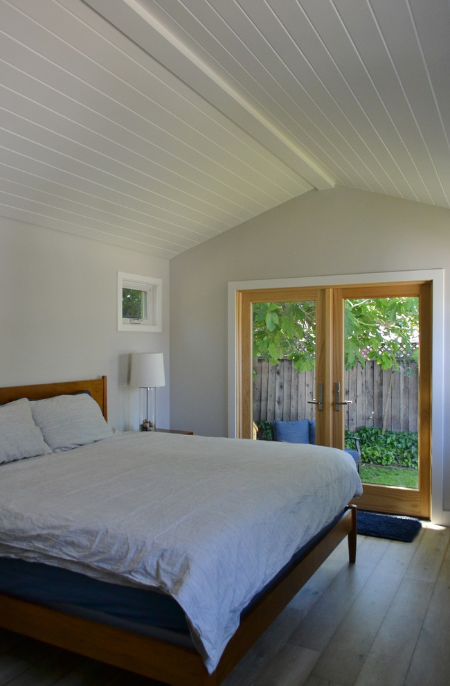 This is an example of a large country bedroom in San Francisco with white walls, medium hardwood floors and brown floor.