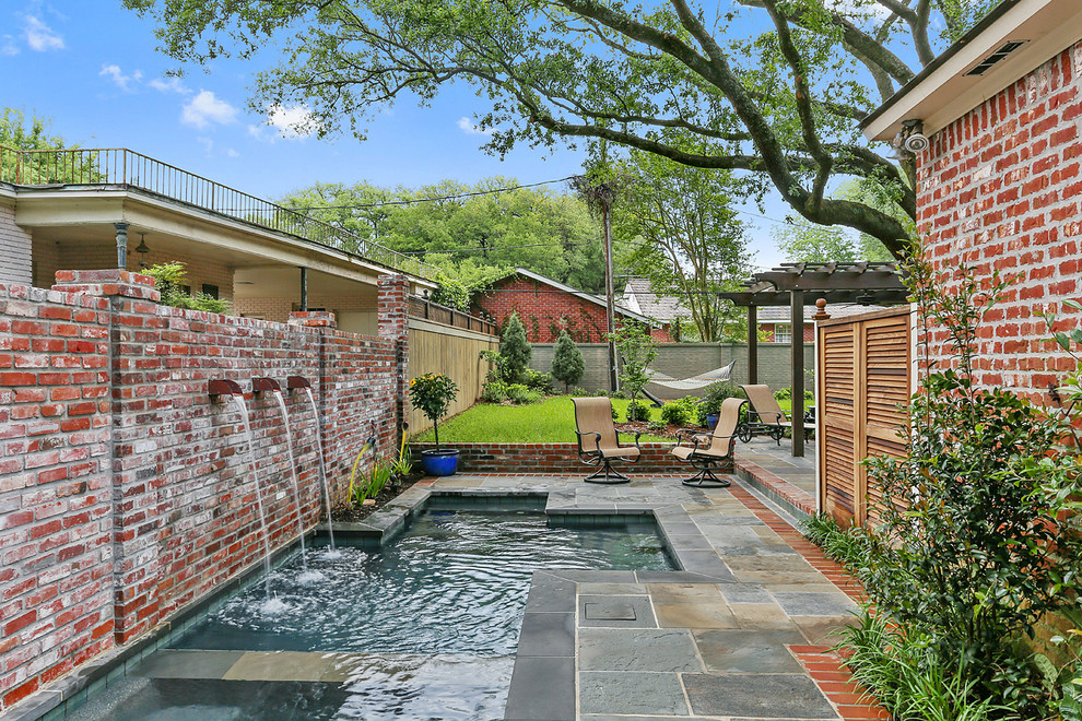 This is an example of a small transitional courtyard custom-shaped natural pool in New Orleans with a hot tub and natural stone pavers.