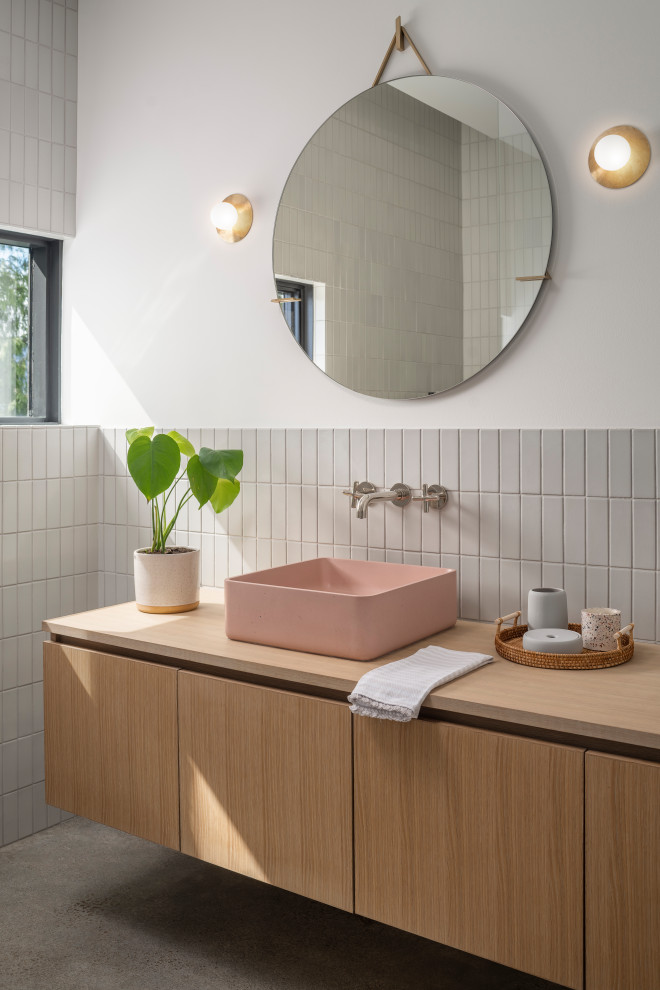 Inredning av ett modernt mellanstort en-suite badrum, med skåp i ljust trä, grå kakel, keramikplattor, betonggolv, träbänkskiva, släta luckor, vita väggar och grått golv