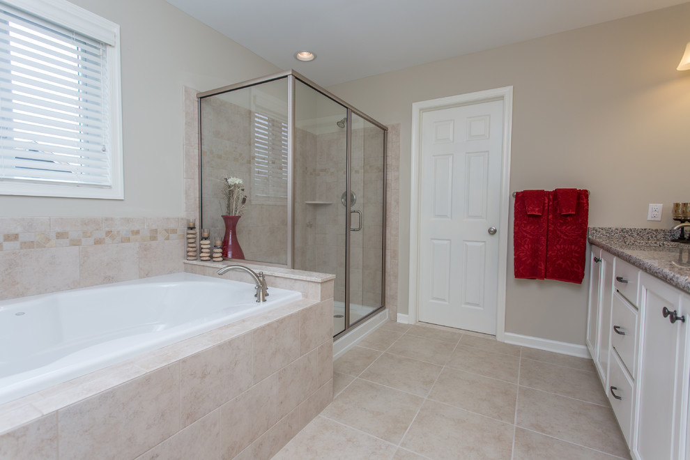 This is an example of a large traditional master bathroom in Philadelphia with beaded inset cabinets, white cabinets, a drop-in tub, a corner shower, beige tile, ceramic tile, beige walls, ceramic floors, an undermount sink and granite benchtops.