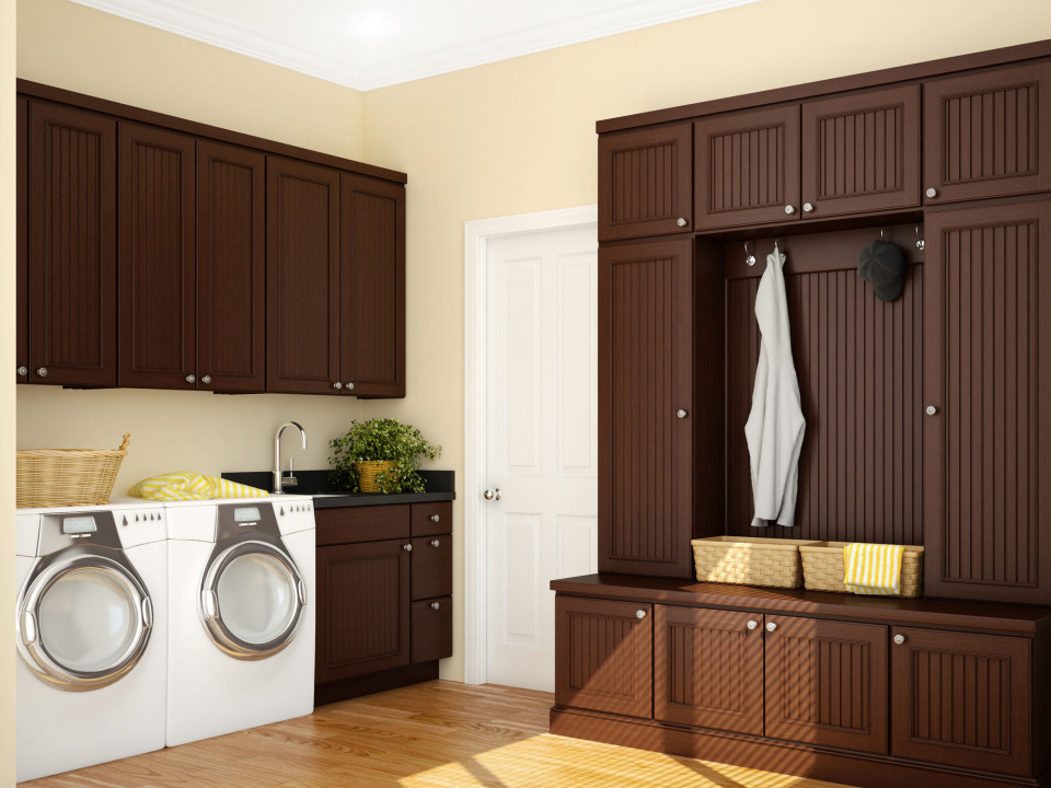 This is an example of a large arts and crafts l-shaped dedicated laundry room in Other with an undermount sink, recessed-panel cabinets, dark wood cabinets, quartz benchtops, beige walls, light hardwood floors, a side-by-side washer and dryer, beige floor and black benchtop.