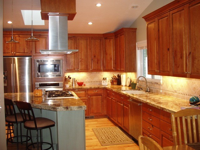 Design ideas for a large transitional l-shaped eat-in kitchen in Salt Lake City with an undermount sink, raised-panel cabinets, medium wood cabinets, granite benchtops, beige splashback, ceramic splashback, stainless steel appliances, with island, beige benchtop, light hardwood floors and beige floor.